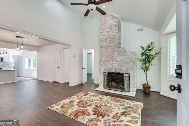 living room featuring ceiling fan, high vaulted ceiling, a stone fireplace, and dark hardwood / wood-style flooring