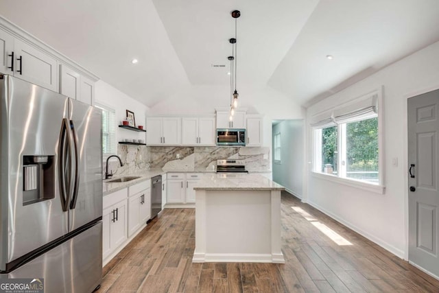 kitchen featuring decorative backsplash, vaulted ceiling, white cabinetry, sink, and stainless steel appliances