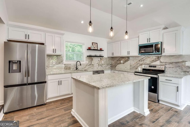 kitchen with appliances with stainless steel finishes, backsplash, white cabinetry, sink, and light wood-type flooring