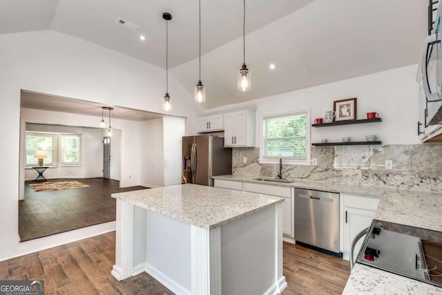 kitchen with tasteful backsplash, vaulted ceiling, appliances with stainless steel finishes, and hardwood / wood-style floors