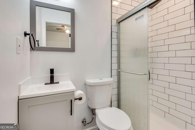 bathroom featuring ceiling fan, a shower with shower door, vanity, and toilet