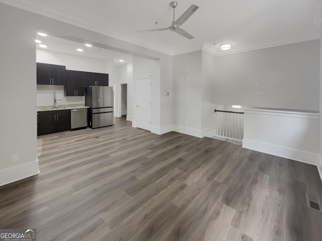 unfurnished living room featuring ornamental molding, sink, ceiling fan, and light wood-type flooring