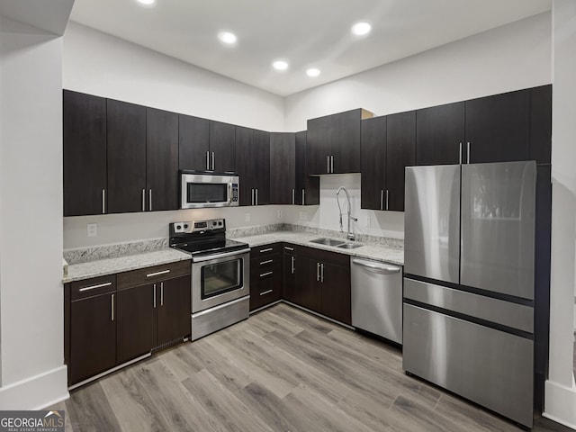 kitchen with stainless steel appliances, light hardwood / wood-style floors, sink, and dark brown cabinets