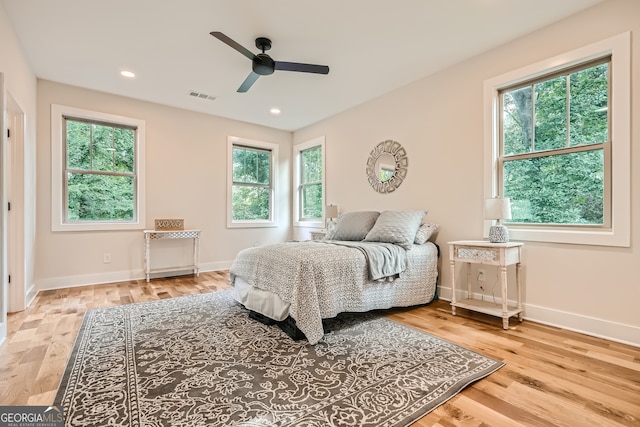 bedroom with ceiling fan, light hardwood / wood-style floors, and multiple windows