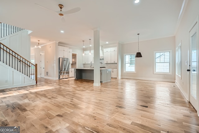 unfurnished living room with sink, light hardwood / wood-style flooring, crown molding, and ceiling fan