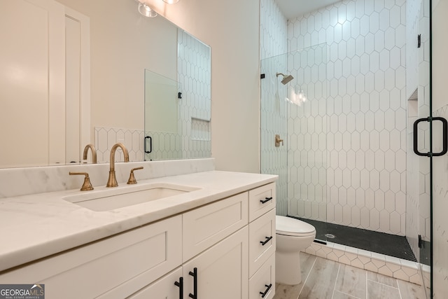 bathroom featuring wood-type flooring, an enclosed shower, vanity, and toilet