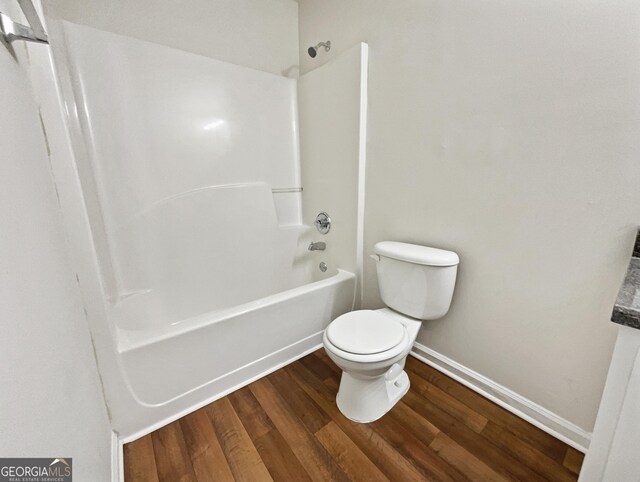 bathroom with toilet, tub / shower combination, and hardwood / wood-style flooring