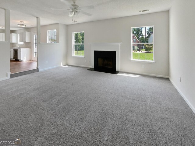 unfurnished living room with carpet floors, sink, ceiling fan, and a textured ceiling