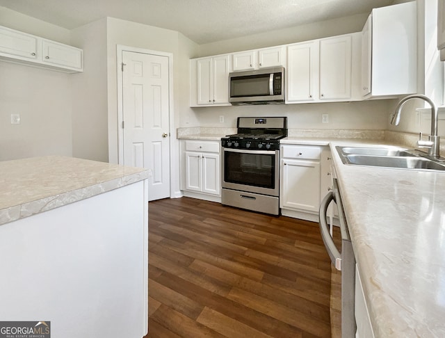 kitchen with sink, white cabinetry, appliances with stainless steel finishes, and dark wood-type flooring