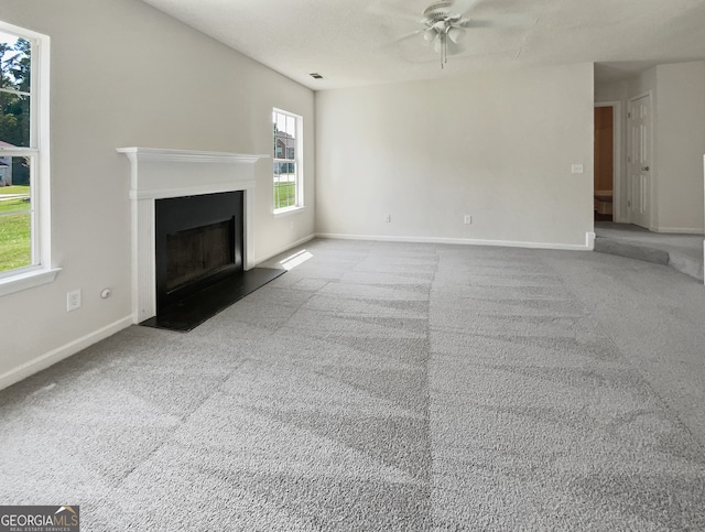 unfurnished living room featuring ceiling fan, plenty of natural light, and carpet