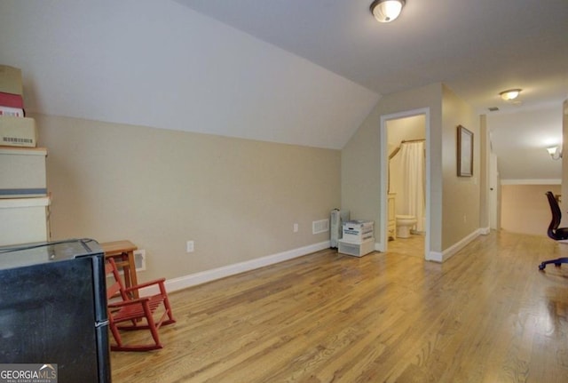 additional living space with vaulted ceiling and light hardwood / wood-style floors