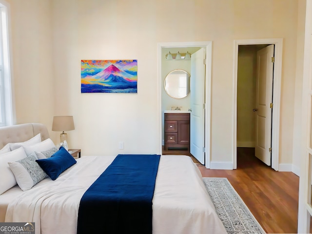 bedroom with connected bathroom, sink, and hardwood / wood-style floors