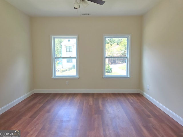 unfurnished room featuring dark wood-style floors, a ceiling fan, and baseboards