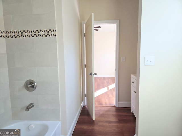 full bath featuring baseboards, wood finished floors, and bathtub / shower combination