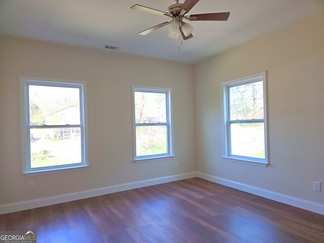 spare room featuring plenty of natural light, ceiling fan, and dark hardwood / wood-style flooring