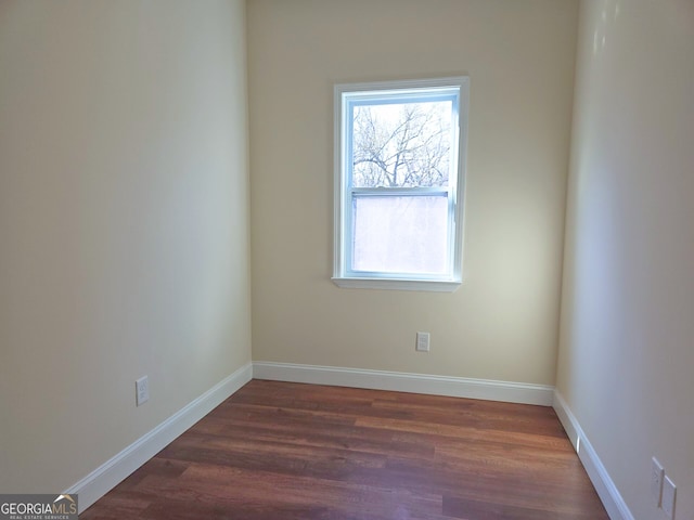 unfurnished room with dark wood finished floors and baseboards