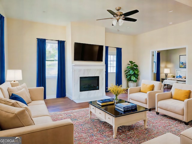 living room featuring a premium fireplace, a ceiling fan, and wood finished floors