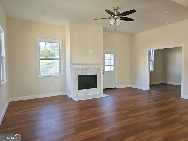 unfurnished living room featuring ceiling fan, dark hardwood / wood-style floors, and a premium fireplace