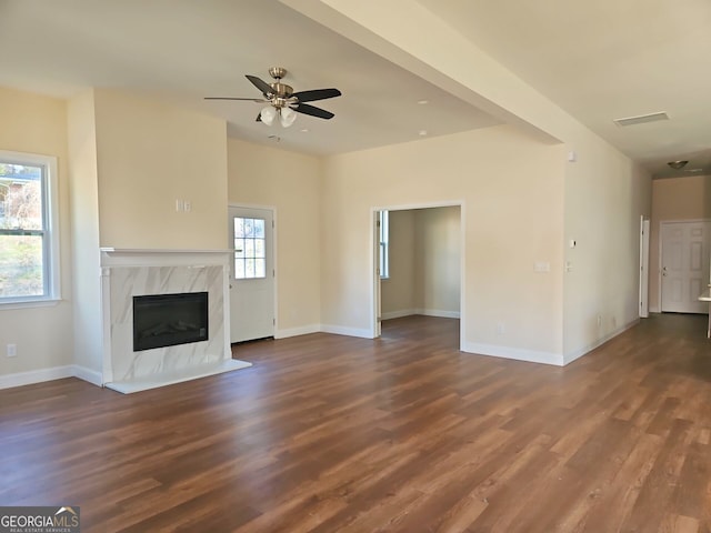 unfurnished living room featuring wood finished floors, baseboards, visible vents, a premium fireplace, and ceiling fan