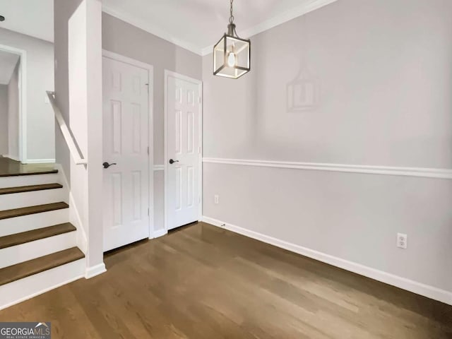 unfurnished dining area with crown molding, dark wood-type flooring, stairway, and baseboards