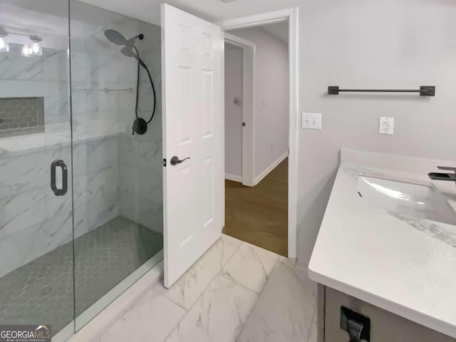 bathroom with marble finish floor, a marble finish shower, vanity, and baseboards