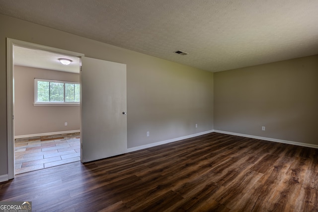 unfurnished room with hardwood / wood-style flooring and a textured ceiling