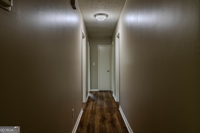 hallway with dark hardwood / wood-style floors and a textured ceiling