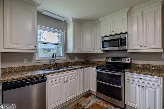 kitchen featuring light tile patterned flooring, sink, dark stone countertops, white cabinetry, and stainless steel appliances