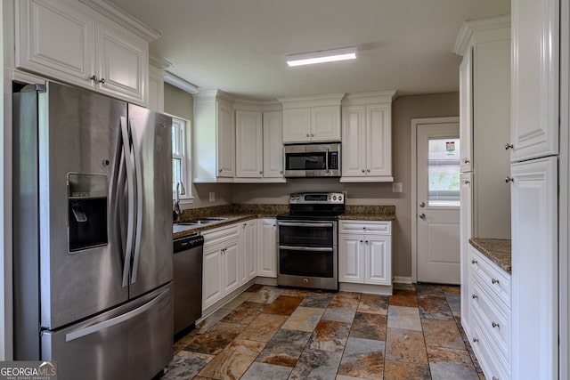 kitchen with sink, white cabinets, dark tile patterned floors, and stainless steel appliances