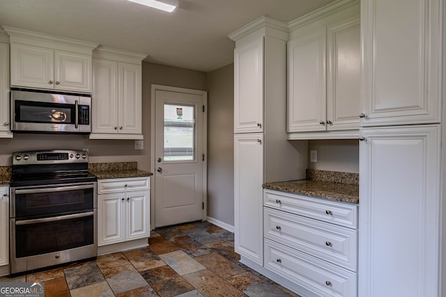 kitchen with white cabinets, dark stone countertops, appliances with stainless steel finishes, and dark tile patterned floors