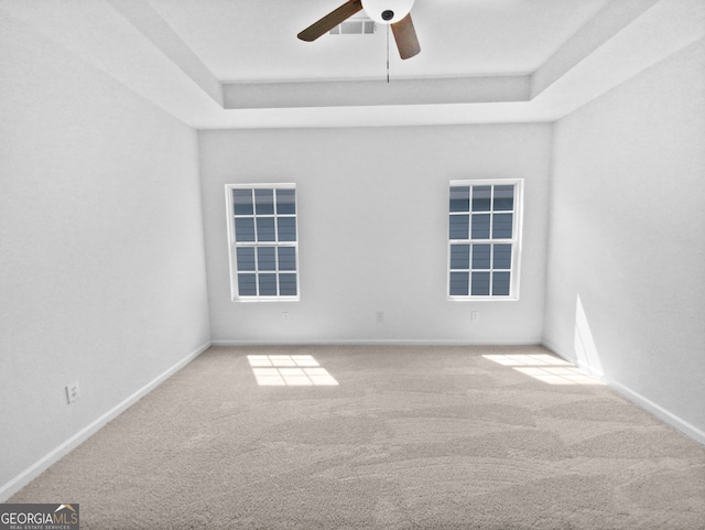 carpeted empty room featuring ceiling fan and a tray ceiling