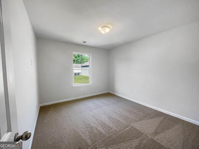 spare room with carpet flooring, visible vents, and baseboards