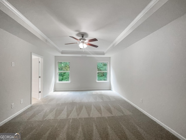 spare room with carpet, a raised ceiling, a ceiling fan, and baseboards