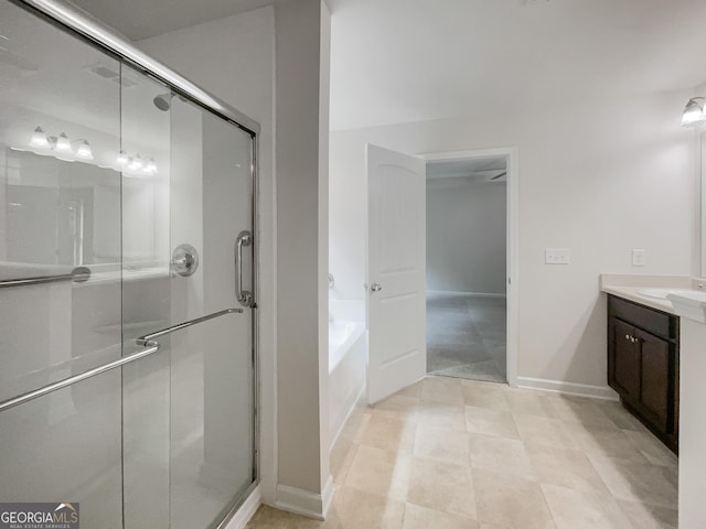 full bathroom with a stall shower, vanity, a bath, and baseboards