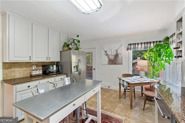 kitchen with a wealth of natural light, stainless steel fridge with ice dispenser, light tile patterned floors, and tasteful backsplash