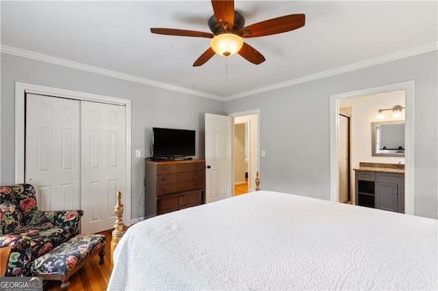 bedroom with ceiling fan, hardwood / wood-style floors, a closet, connected bathroom, and crown molding