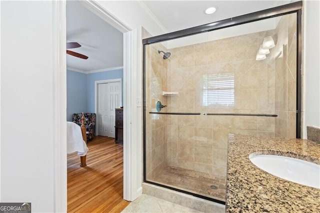 bathroom with ceiling fan, an enclosed shower, vanity, ornamental molding, and tile patterned floors