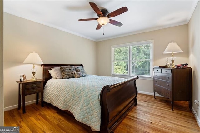 bedroom featuring hardwood / wood-style floors, ornamental molding, and ceiling fan