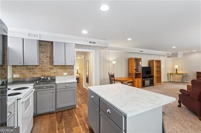 kitchen featuring a center island, white electric range oven, wood-type flooring, decorative backsplash, and gray cabinets