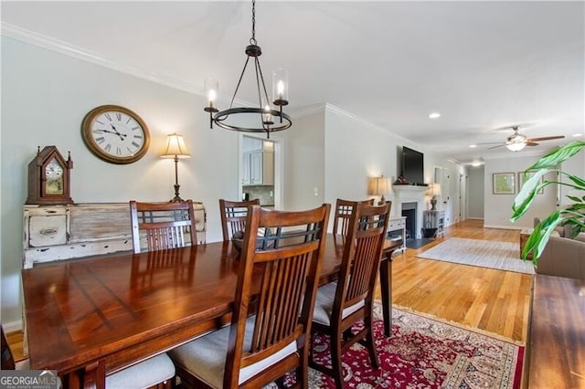 dining area with ceiling fan with notable chandelier, hardwood / wood-style floors, and ornamental molding