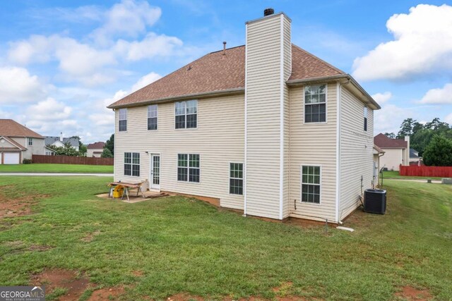 rear view of property featuring a lawn and central AC