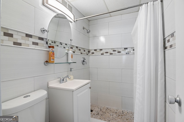 bathroom with toilet, tile walls, curtained shower, and vanity