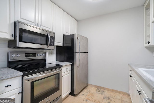 kitchen featuring white cabinets, light stone counters, light tile patterned flooring, and stainless steel appliances