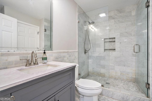 bathroom with backsplash, toilet, an enclosed shower, vanity, and tile walls