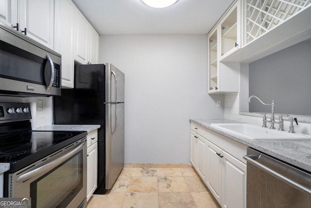 kitchen with white cabinets, light tile patterned flooring, appliances with stainless steel finishes, and light stone countertops