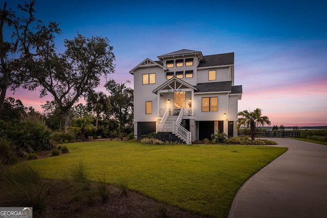 beach home featuring a lawn, fence, and driveway