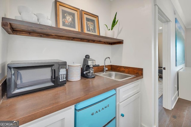 interior space with dark wood-style flooring, refrigerator, black microwave, and a sink