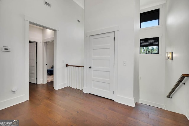 foyer featuring dark wood finished floors, baseboards, visible vents, and a towering ceiling