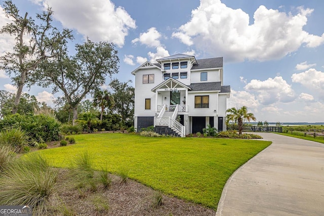 view of front of house with a front yard, concrete driveway, and a shingled roof