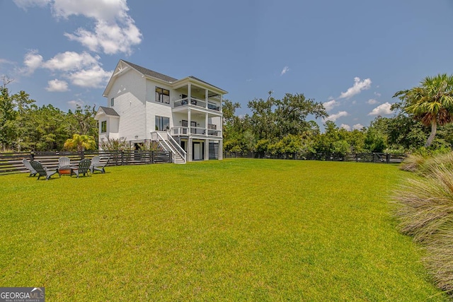 exterior space with a balcony, stairway, a lawn, and fence